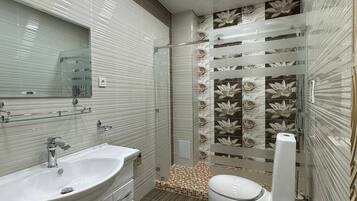 Un baño moderno con un espejo grande, dos lavamanos, un inodoro y un bidé.