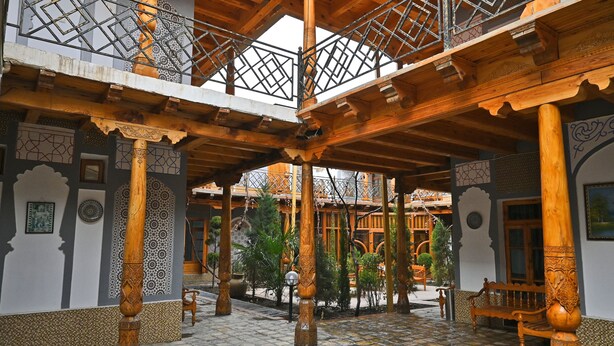 A courtyard with wooden beams, patterned walls, and a tiled floor. - Grand Nodirbek Boutique Hotel - House Museum 17-19 century (Bukhara)