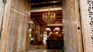 An ornate wooden lobby with intricate carvings, a chandelier, and a patterned carpet. - Grand Nodirbek Boutique Hotel - House Museum 17-19 century (Bukhara)