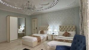 A hotel room with a large bed, a separate sofa, a small table with bottles, and a decorative ceiling piece. - Grand Nodirbek Boutique Hotel - House Museum 17-19 century (Bukhara)