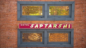 A hotel sign with the name "Saptarshi" on a red background, set in a brick wall with two rectangular windows above it. - Hotel Saptarshi (Bankura)