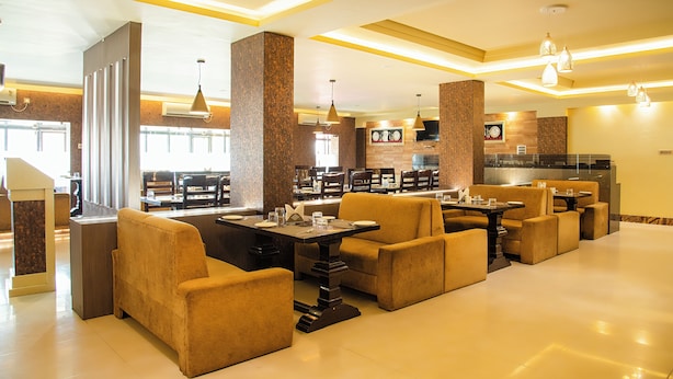 A spacious lobby with multiple seating areas, a reception desk, and a visible kitchen area. - Hotel Saptarshi (Bankura)