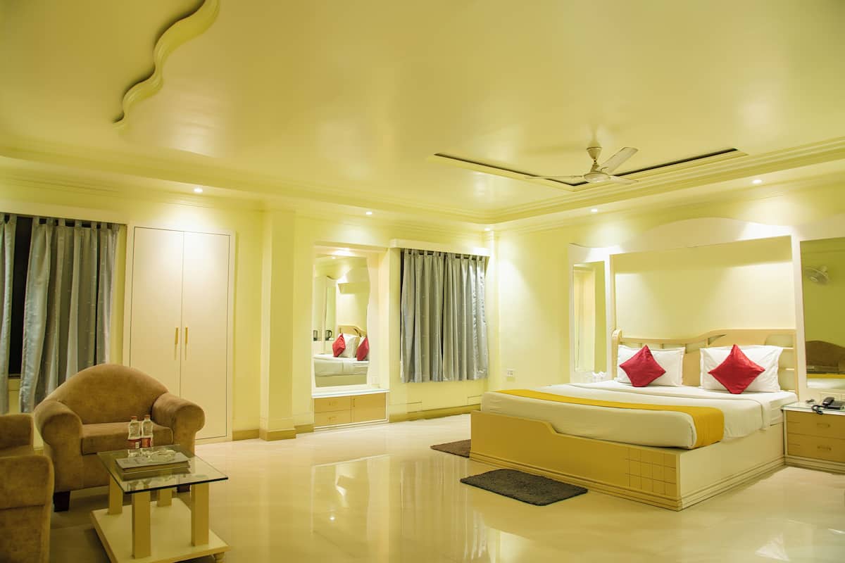 A hotel room with a bed, a chair, a table, and a ceiling fan.