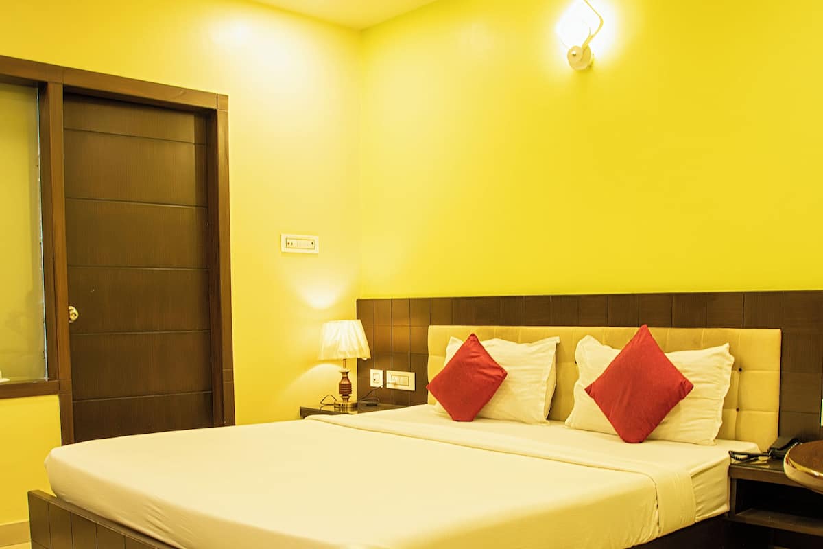 A hotel room with a large bed, a nightstand, a lamp, and a ceiling fan.