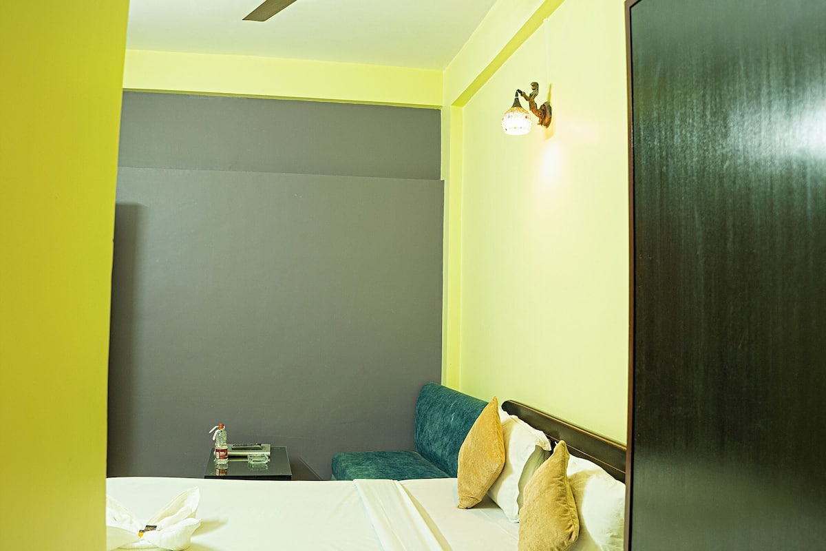 A bedroom with a bed, a ceiling fan, a nightstand, and a wardrobe.