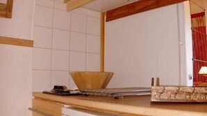A compact kitchen with wooden cabinets, a white refrigerator, and a tiled backsplash. - 100m from ski slopes, 4th floor, view mountain, tv, ski locker, 61m², Valmorel (Valmorel)