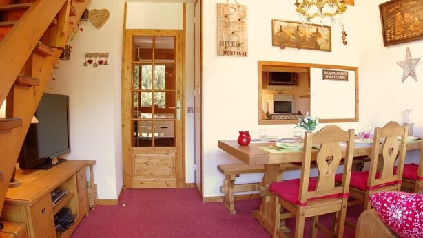 A cozy dining area with wooden furniture, a television, and a sign indicating a restaurant at altitude. - 100m from ski slopes, 4th floor, view mountain, tv, ski locker, 61m², Valmorel (Valmorel)