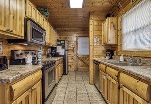 Una cocina con armarios de madera, encimeras de granito, electrodomésticos de acero inoxidable y suelo de baldosas.