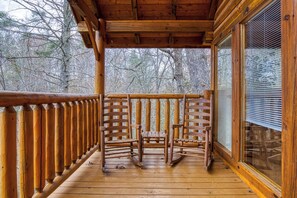 Una terraza de madera con una mecedora y una cerca de madera.
