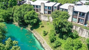 Un hotel moderno con edificios de varios pisos, un río y abundante vegetación.
