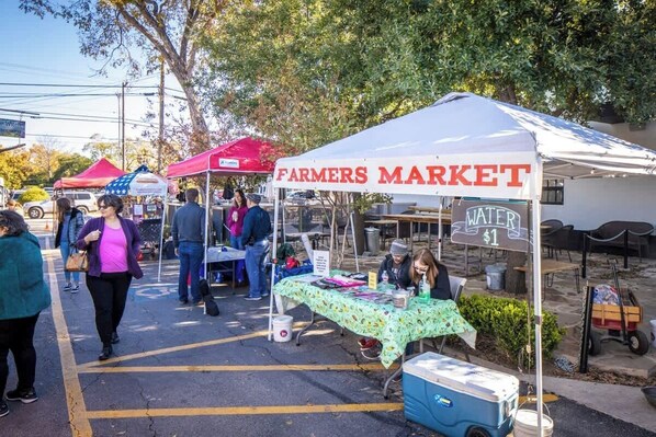 A farmers market with a tent labeled 'Farmers Market' and a sign for 'Water $1'.