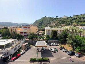 Un’area di parcheggio con diverse auto, una stazione di servizio e edifici con balconi.