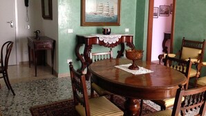 Un comedor con una mesa redonda de madera, sillas y una araña.