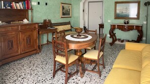 Comedor con mesa de madera, sillas, candelabro, estantería y un cuadro en la pared.