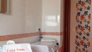 Un baño con lavadora, toalla y espejo.