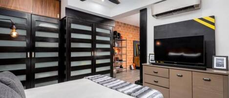 Une chambre à coucher avec un lit, une armoire, une télévision et un ventilateur de plafond.