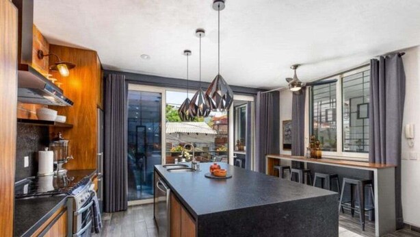 Una cucina moderna con isola centrale, mobili in legno e illuminazione a sospensione.