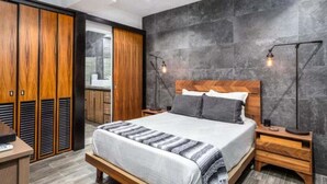Una camera da letto moderna con un letto grande, un'armadio in legno e una parete in pietra.
