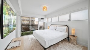Ein modernes Schlafzimmer mit einem großen Bett, Blick auf einen Balkon und einer Deckenleuchte.