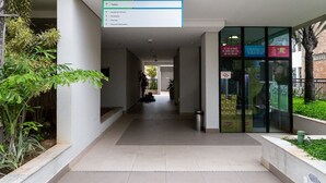 A corridor with directional signs, a trash bin, and a glass door with advertisements. - Capital Brás - Negócios e Lazer (São Paulo)