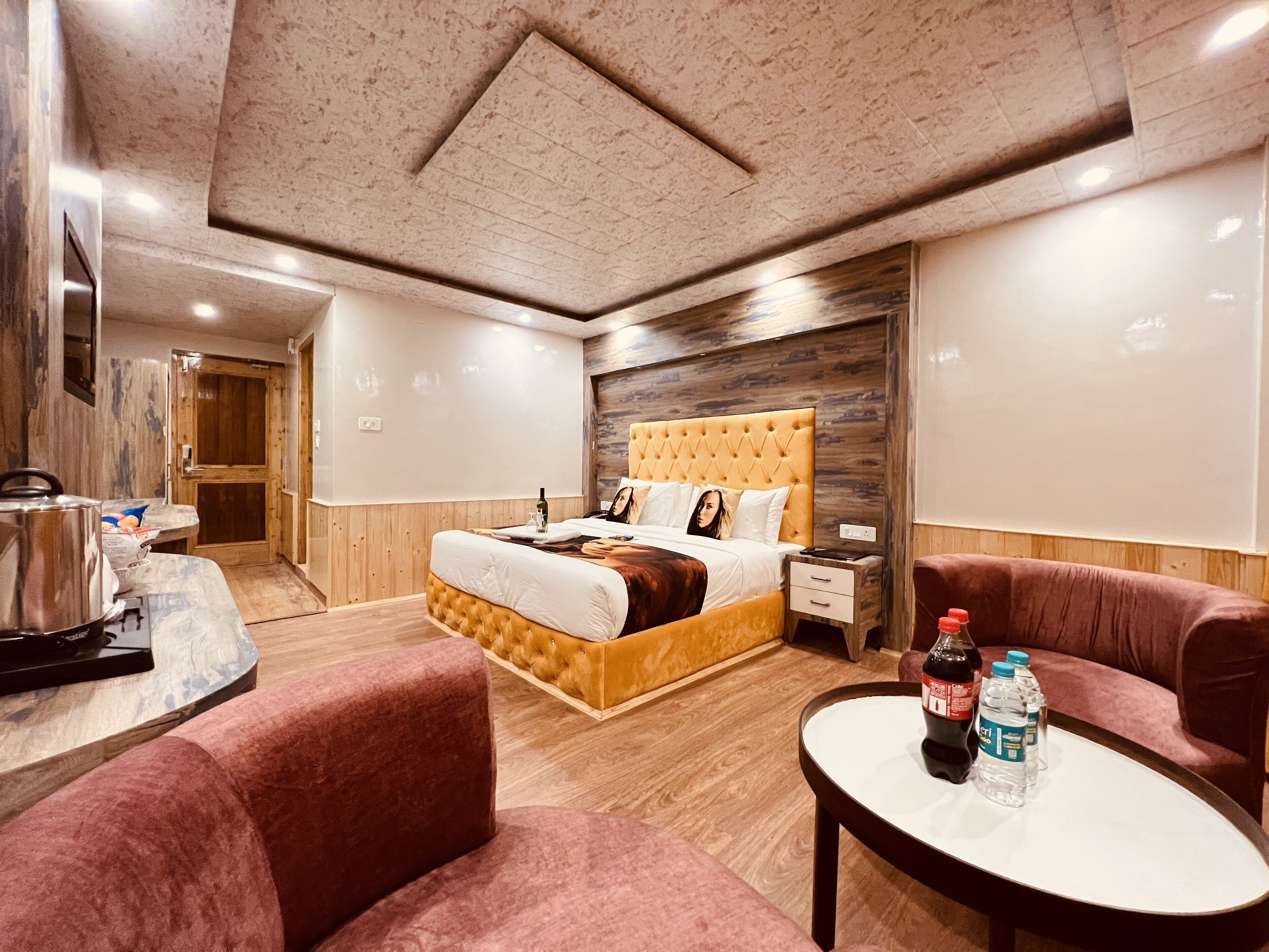 Ein modernes Hotelzimmer mit einem großen Bett, einem Holzkopfende, einer Marmorarbeitsplatte und einer Sitzecke mit zwei Stühlen und einem kleinen Tisch.