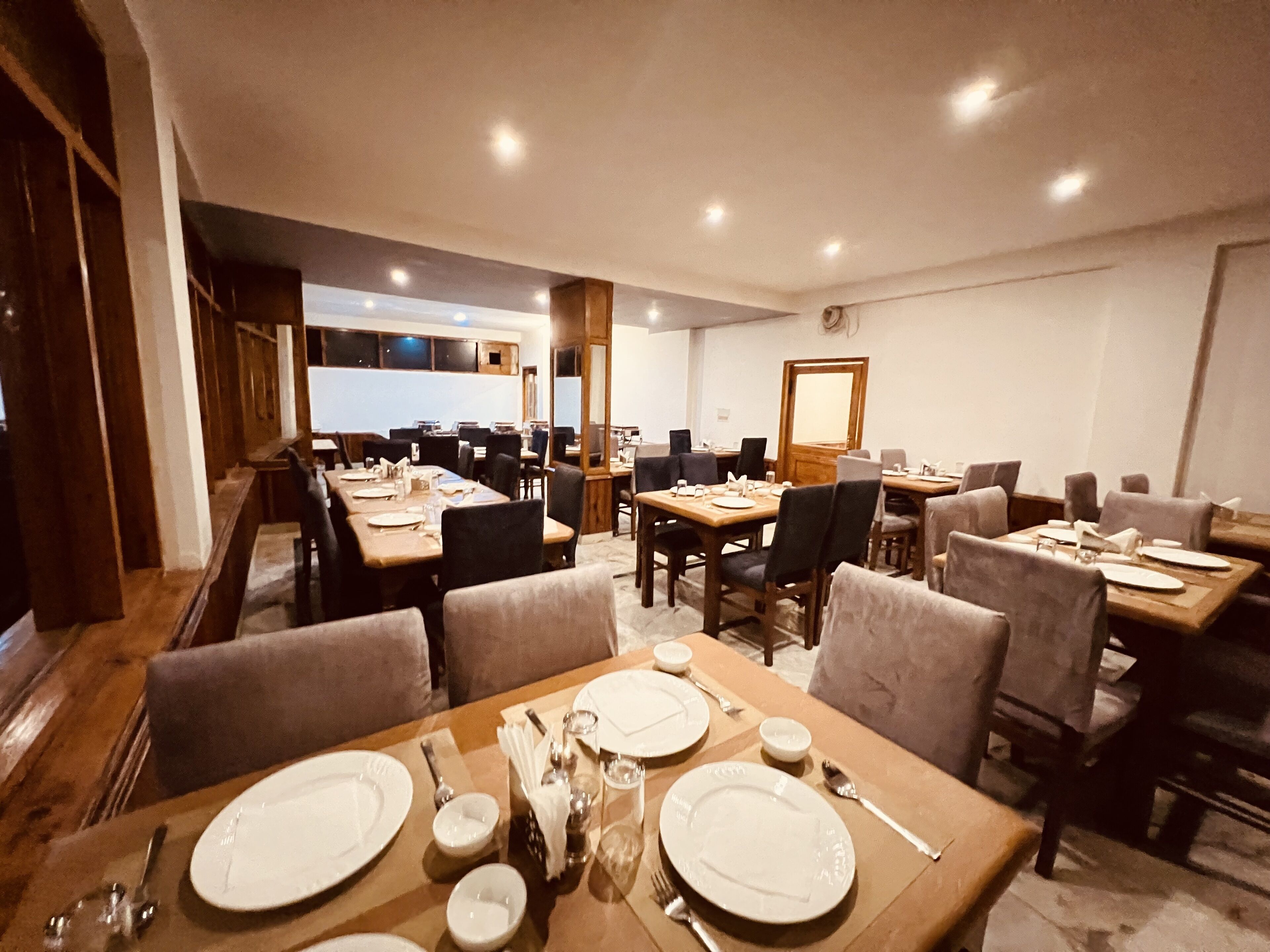 A dining area with multiple tables set for meals, featuring chairs and dining essentials.