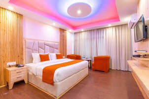 Habitación de hotel con una cama grande, un escritorio, una silla y un televisor.