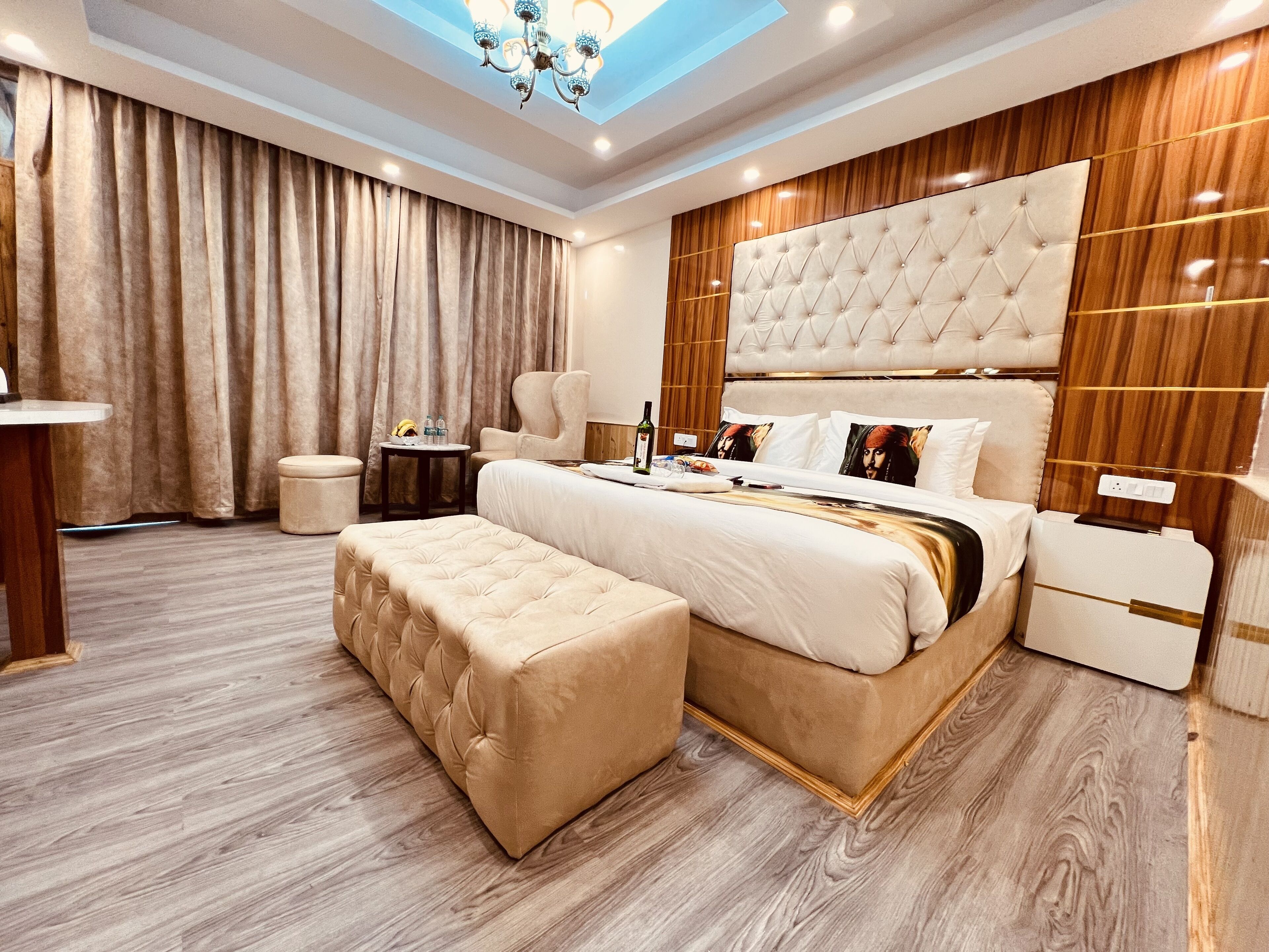 A modern hotel room with a large bed, a sitting area, and a small table with amenities.