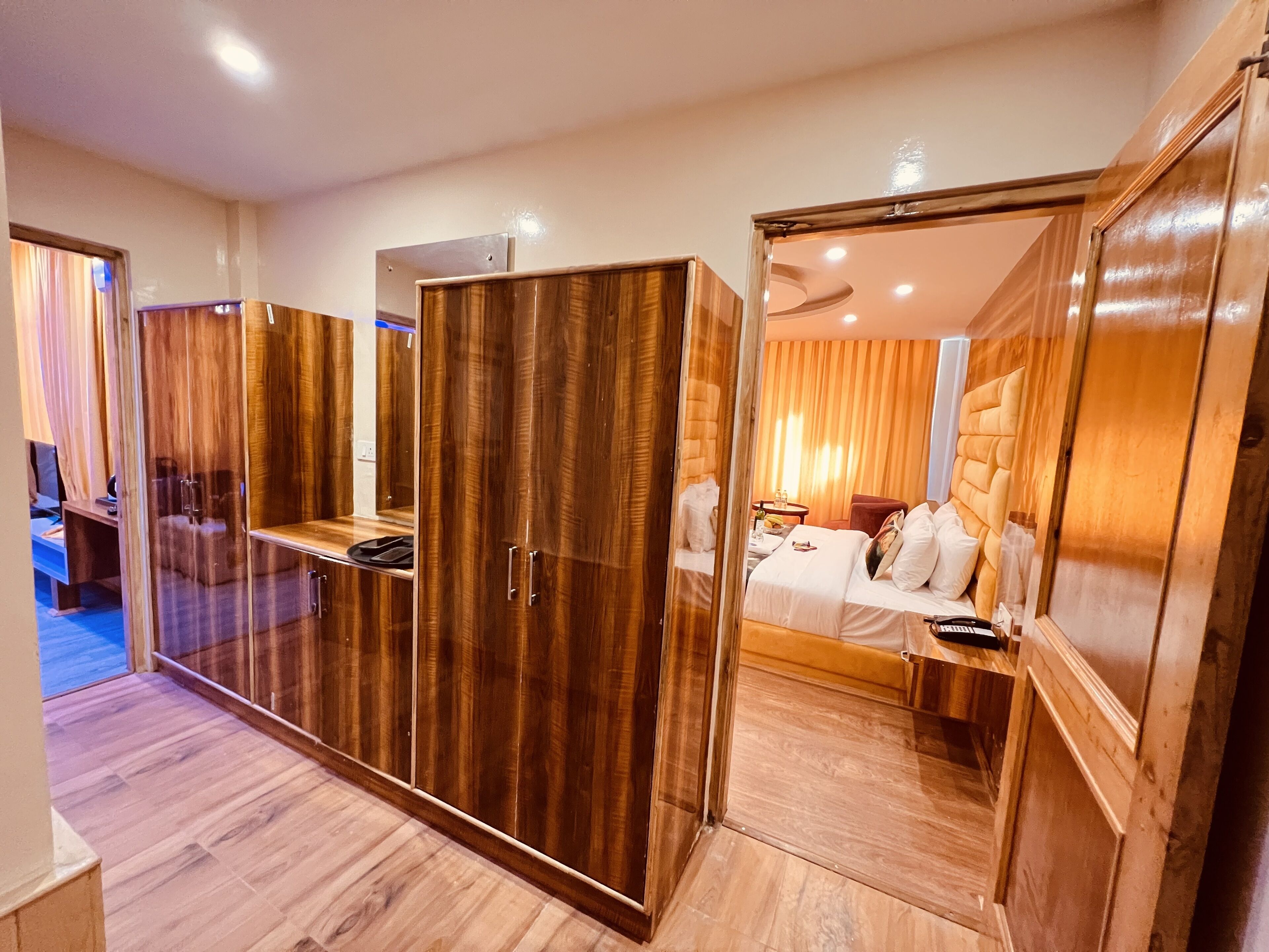 Una habitación de hotel con un armario de madera, una cama, un escritorio y un espejo.