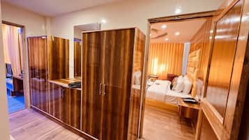 Una habitación de hotel con un armario de madera, una cama, un escritorio y un espejo.