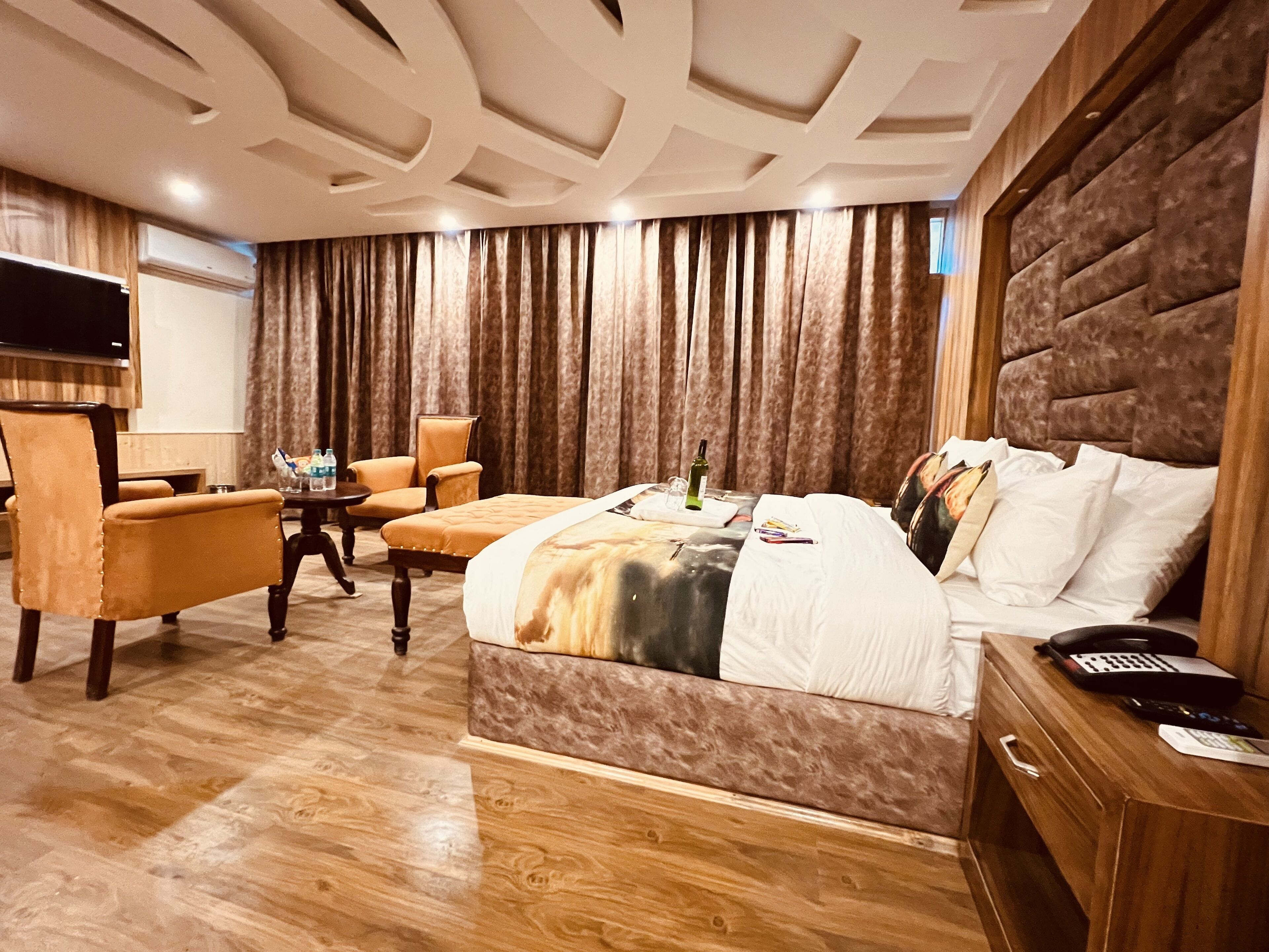 Une chambre d’hôtel équipée d’un lit, d’un bureau, d’une chaise, d’une télévision et d’une fenêtre avec des rideaux.