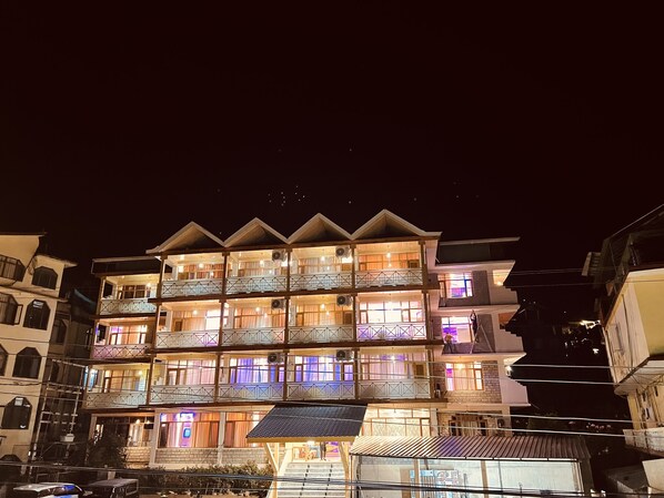 A multi-story hotel with balconies, a covered entrance, and a visible staircase.