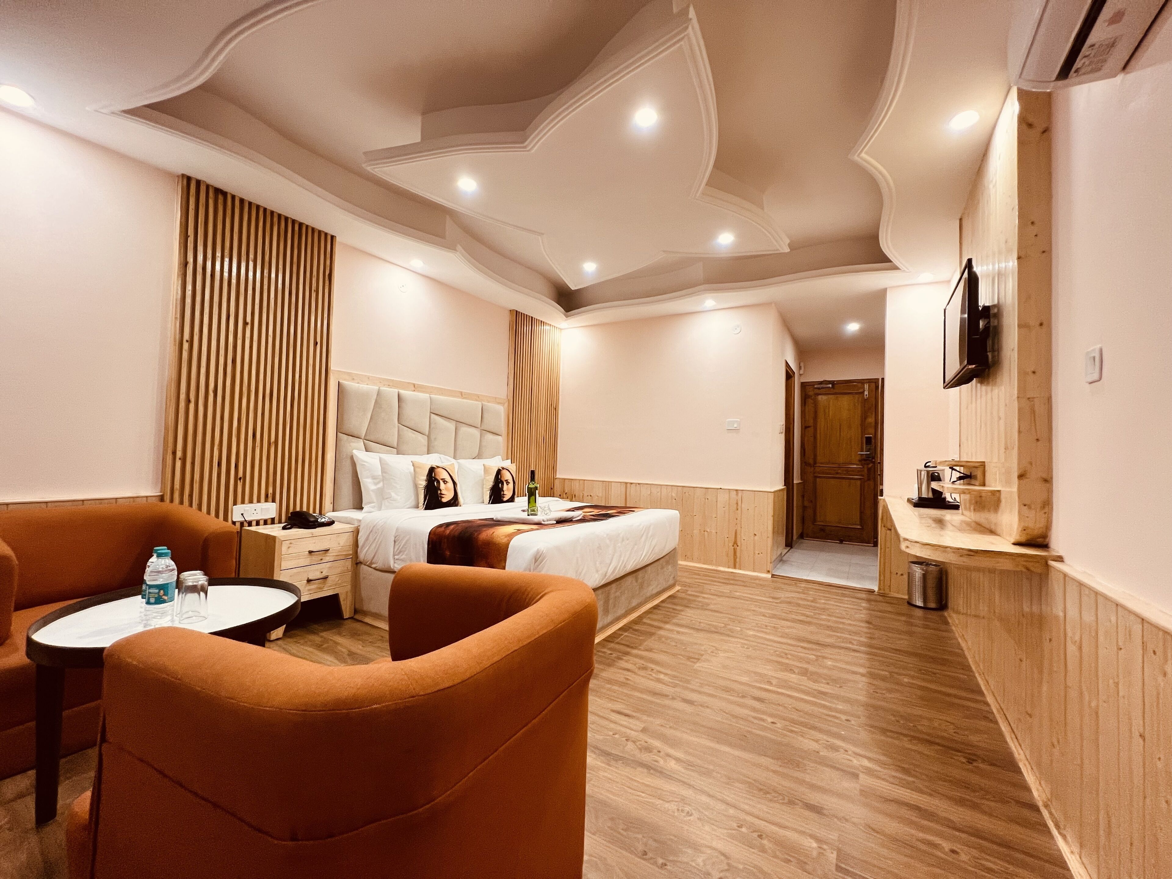 A hotel room with a bed, a desk, a chair, a TV, and a wooden panel wall.
