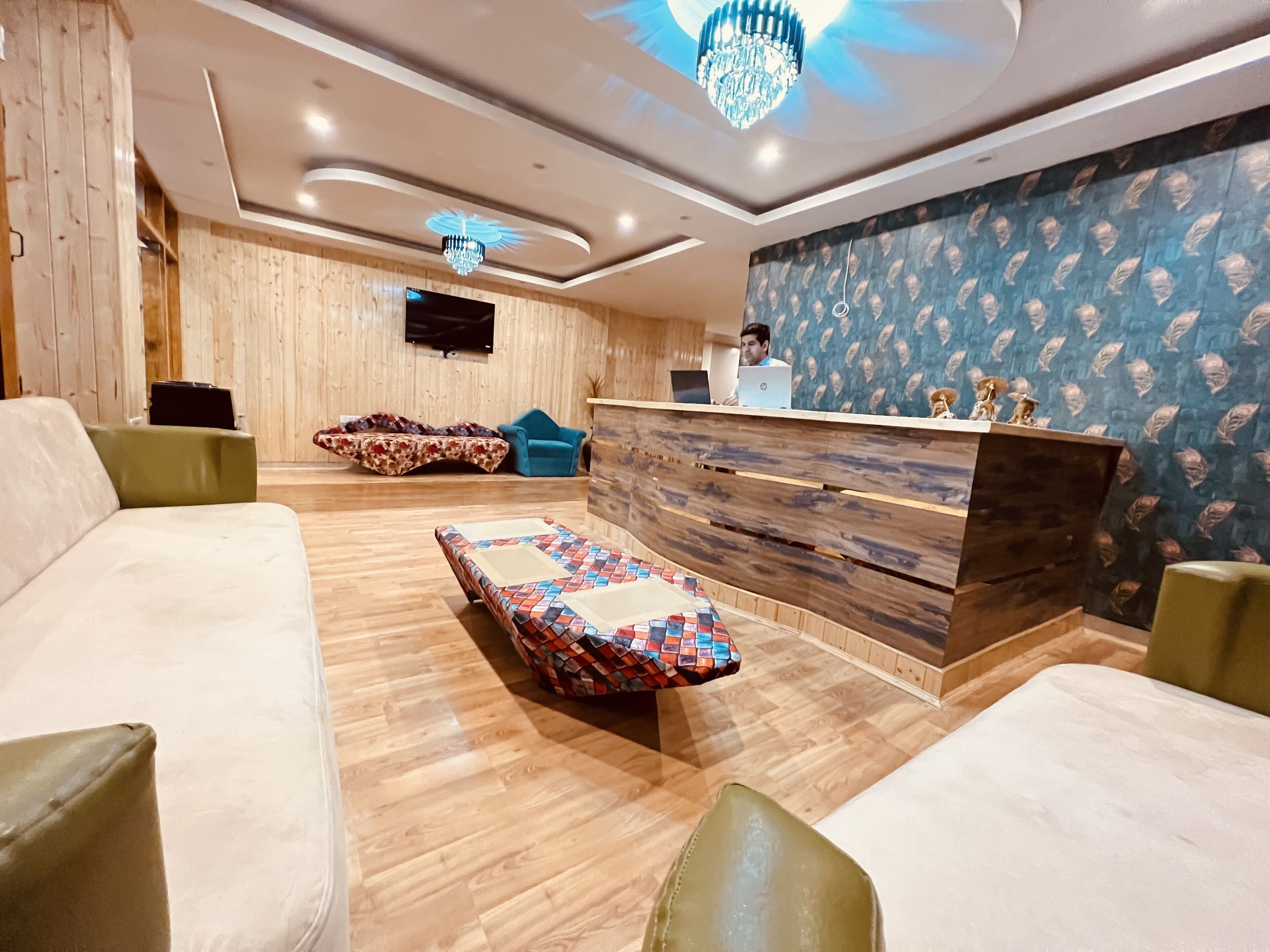 A modern reception area with a wooden reception desk, a patterned sofa, and a lounge chair.