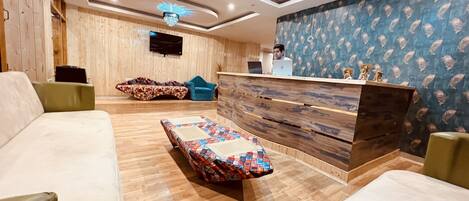 A modern reception area with a wooden reception desk, a patterned sofa, and a lounge chair.