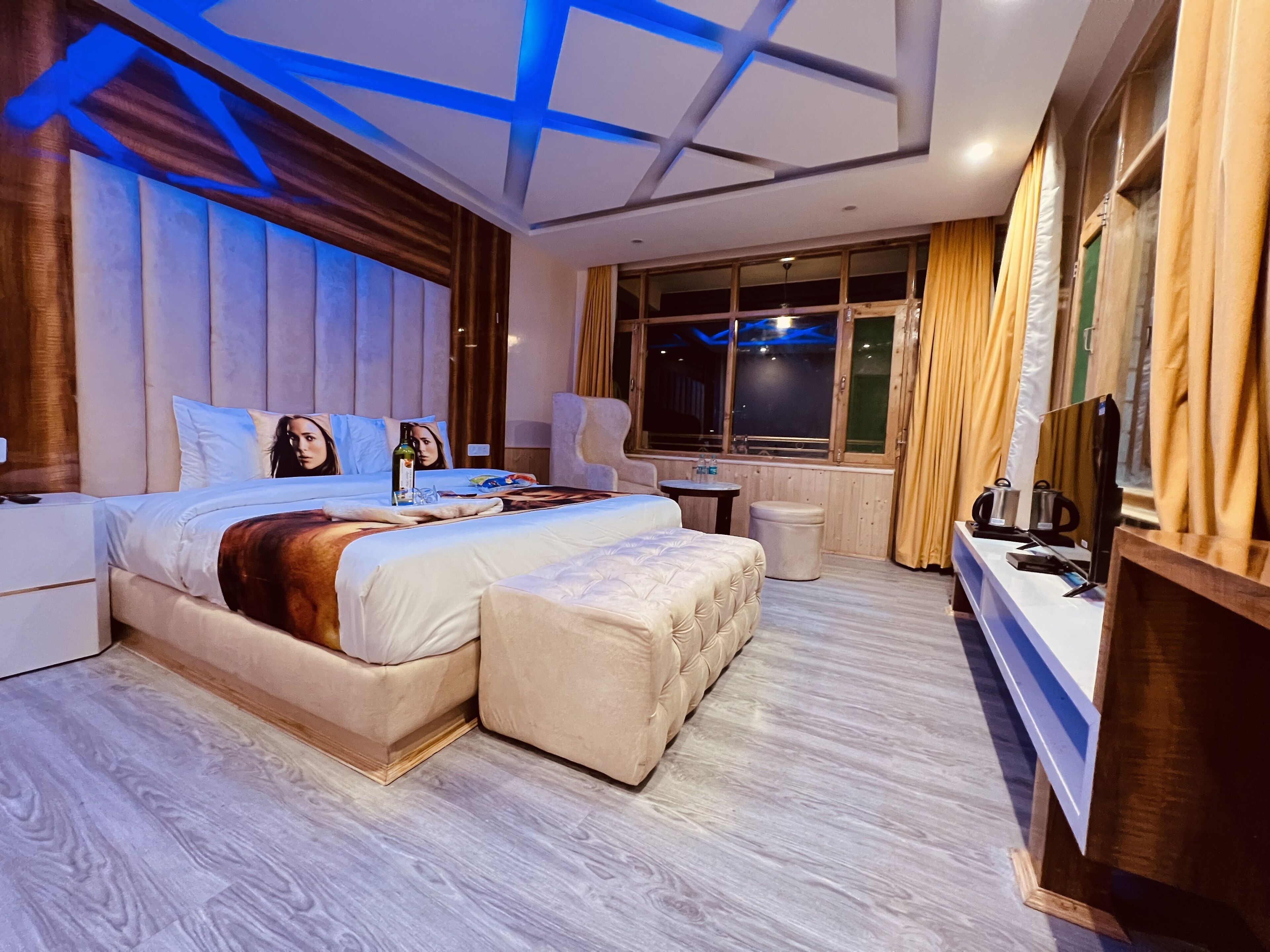 A modern hotel room with a large bed, a small table, a chair, and a TV.