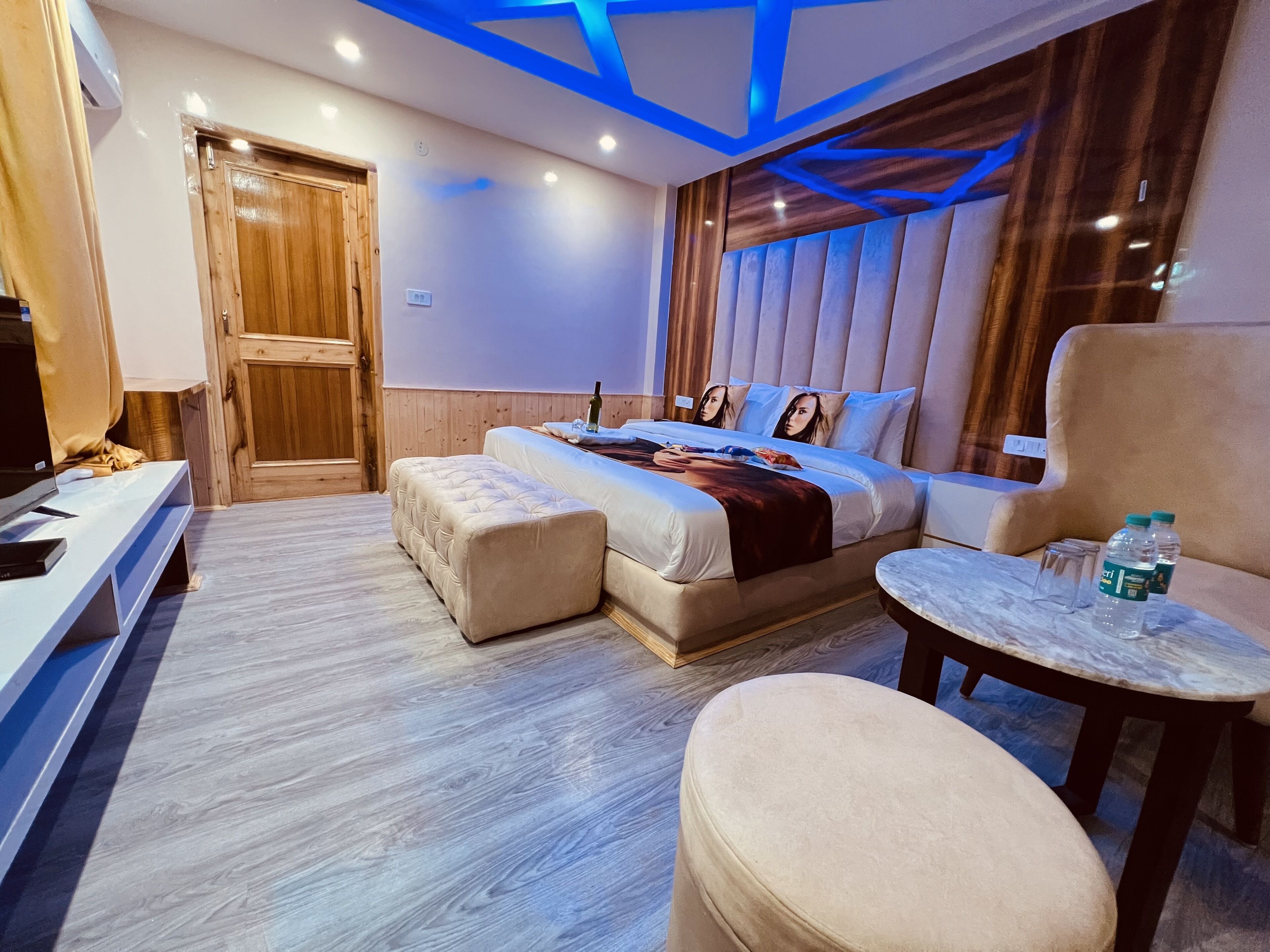 A modern hotel room with a bed, a seating area, and a TV.