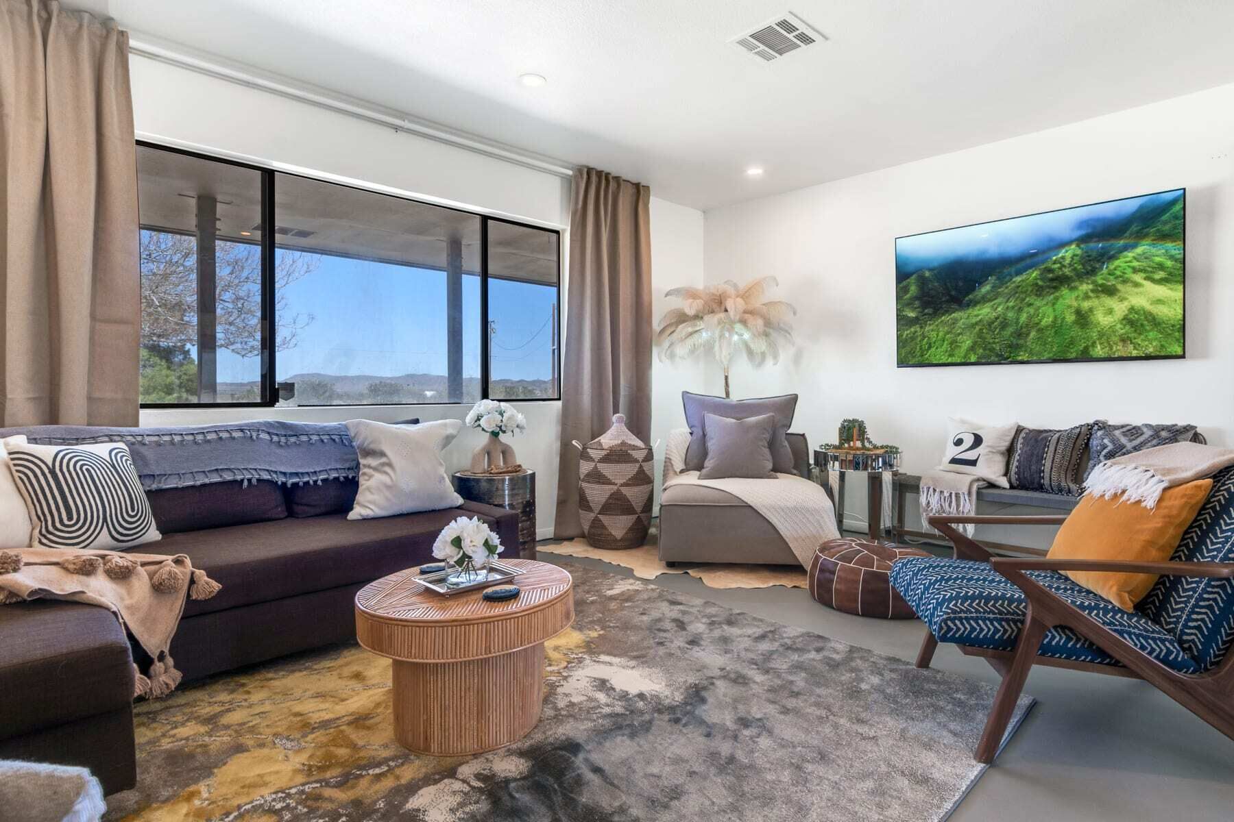 Una sala de estar moderna con sofá, sillón, mesa de centro y un ventanal que ofrece vistas al exterior.