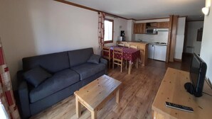 Ein kompakter Wohnbereich mit Sofa, Esstisch und Küchenzeile.