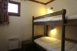 A bunk bed room with a window, a bedside lamp, and a small wooden stool. - 1st floor, balcony, tv, ski locker, 59m², Aussois (Aussois)