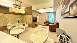 A modern living room with a dining area, a flat-screen TV, and a sofa.