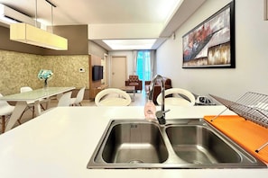 A modern hotel room with a kitchen area, dining table, and seating.
