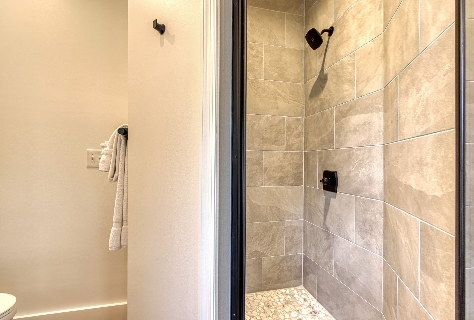 Une douche avec des carreaux de couleur beige et une porte en verre.