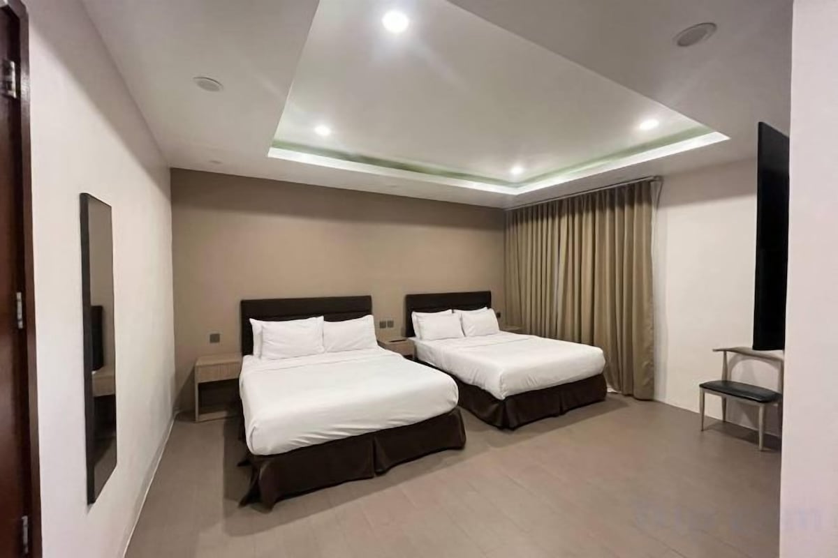 A hotel room with two beds, a flat-screen TV, a desk, and a chair.
