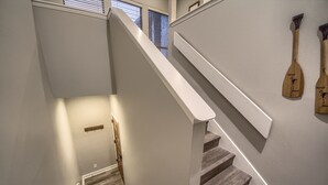 A staircase with wooden steps and white walls, leading to a landing area with a small window and a wooden paddle on the wall. - Cw B202 Camp Warnecke B202 3 Bedroom Condo by RedAwning (New Braunfels)