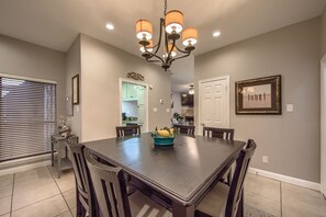 A dining area with a large table, chairs, a chandelier, and a kitchen in the background. - Cw B202 Camp Warnecke B202 3 Bedroom Condo by RedAwning (New Braunfels)