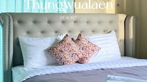 Una cama con cabecera capitonada, dos almohadas y una colcha blanca.