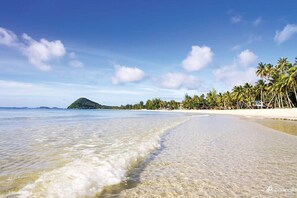 A beach with clear water, a sandy shore, and palm trees. - Thungwua laen resort (Pathio)