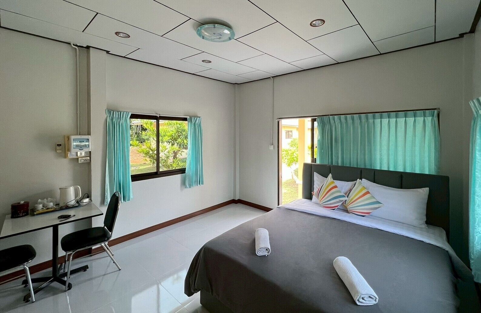 Habitación de hotel con cama, escritorio, silla y ventana con cortinas.