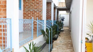 A narrow, stone-paved corridor with blue railings and potted plants. - Rafas Pousada Encantos de Minas  (Tres Coracoes)